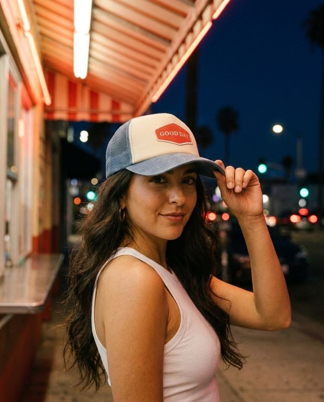 AI variant: woman in GOOD DAY cap at night under a neon-lit awning